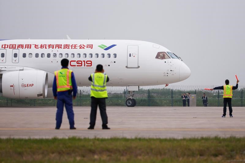 © Reuters. Members of staff stand in front of China's home-grown C919 passenger jet after it landed on its maiden flight at the Pudong International Airport in Shanghai