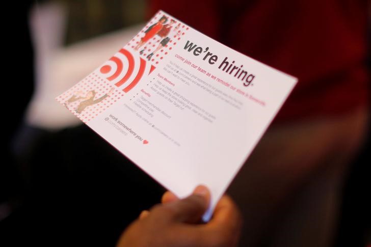 © Reuters. Pessoa em busca de emprego segura papel com a frase "Estamos Contratando" em uma loja de Boston