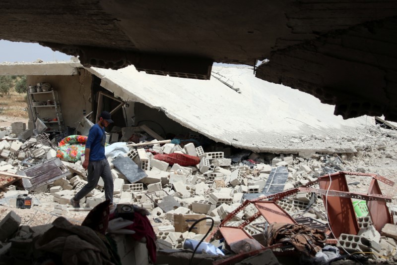 © Reuters. A man walks on the rubble of damaged housing for internally displaced people at a site hit yesterday by barrel bombs in a rebel-held area, south of Deraa city