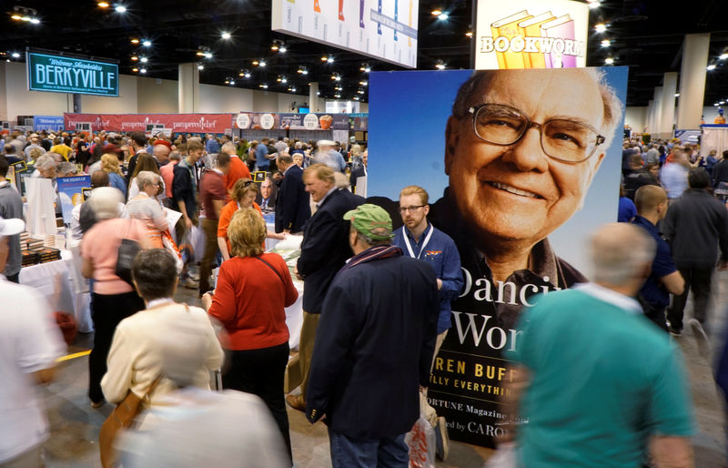 © Reuters. Berkshire Hathaway shareholders walks by a photo of CEO Buffett at the shareholder shopping day in Omaha