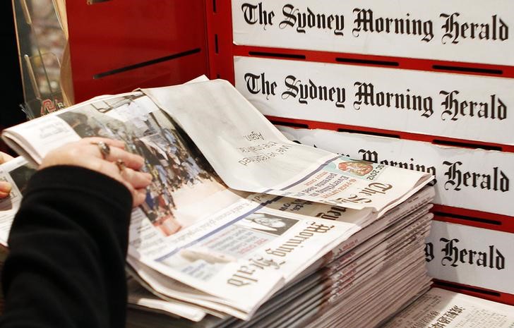© Reuters. A woman picks up a copy of the Sydney Morning Herald newspaper, a Fairfax Media publication, in Sydney