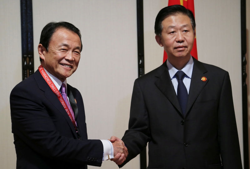 © Reuters. Chinese Finance Minister Xiao Jie (R) and Japanese Finance Minister Taro Aso shake hands in Yokohama