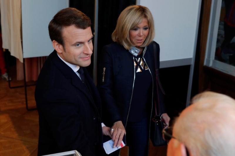 © Reuters. French presidential election candidate Emmanuel Macron, head of the political movement En Marche !, or Onwards ! and his wife Brigitte Trogneux hold hands after voting in Le Touquet