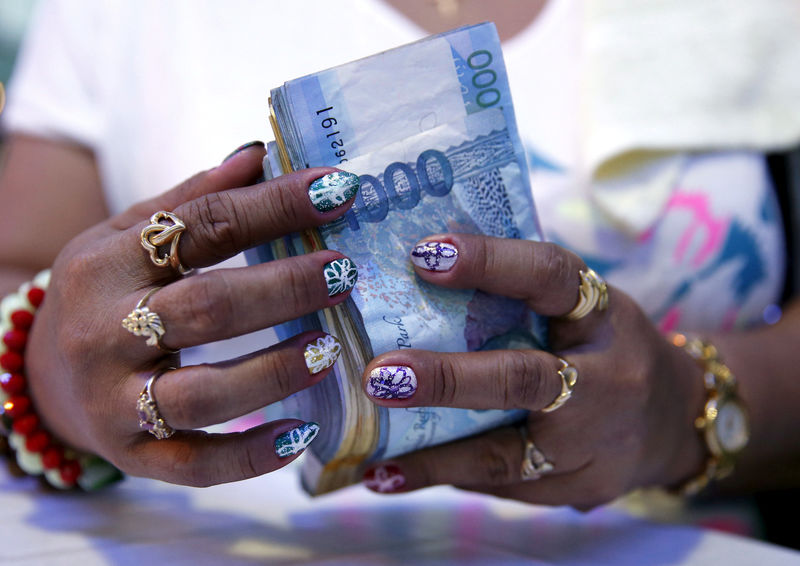 © Reuters. A casino financier wearing rings and with painted fingernails, counts money in Angeles city, north of Manila