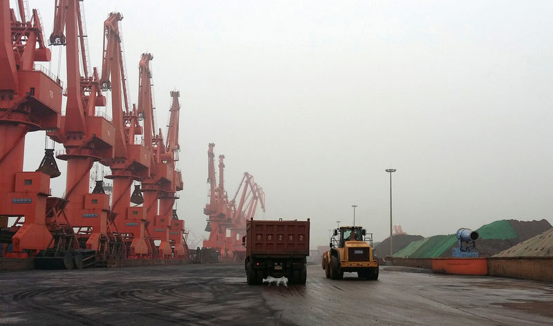 © Reuters. FILE PHOTO: Trucks drive inside an iron ore dump site at the Huanggang Terminal of Qingdao Port, in Qingdao