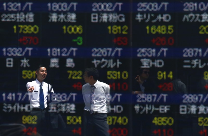 © Reuters. Men are refelcted in a screen displaying market indices outside a brokerage in Tokyo