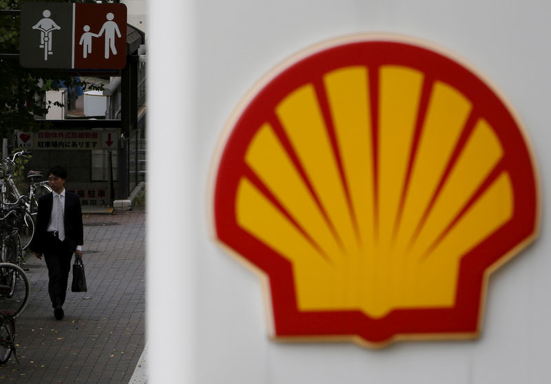 © Reuters. FILE PHOTO: A man walks behind a signboard of Showa Shell Sekiyu at its gas station in Tokyo