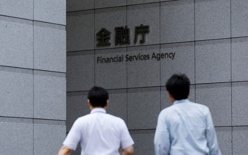 © Reuters. Men walk toward a sign of Japan's Financial Services Agency in Tokyo