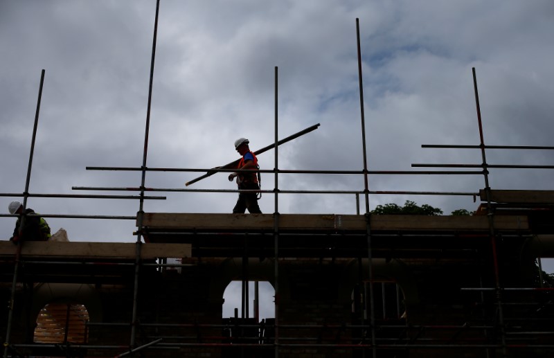 © Reuters. FILE PHOTO - A builder assembles scaffolding as he works on new homes being built for private sale on a council housing estate, in south London