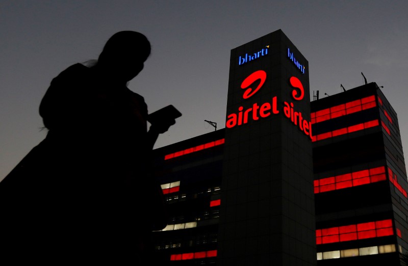 © Reuters. A girl checks her mobile phone as she walks past the Bharti Airtel office building in Gurugram