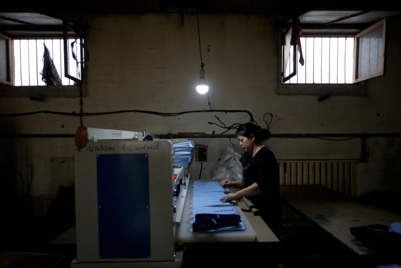 © Reuters. FILE PHOTO: A woman works at Tongfa shoe factory in Santai town of Anxin county