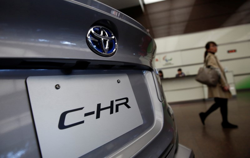 © Reuters. A woman walks past Toyota Motor Corp's C-HR model which is displayed at its headquarters in Tokyo