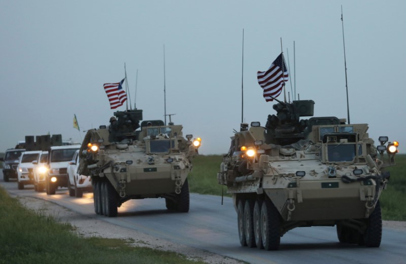 © Reuters. U.S military vehicles and Kurdish fighters from the People's Protection Units (YPG) drive in the town of Darbasiya next to the Turkish border