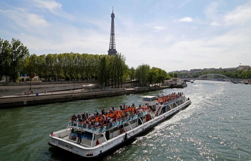 © Reuters. Tourists enjoy a boat trip on the Seine river past the Eiffel Tower on a sunny spring day in Paris, France