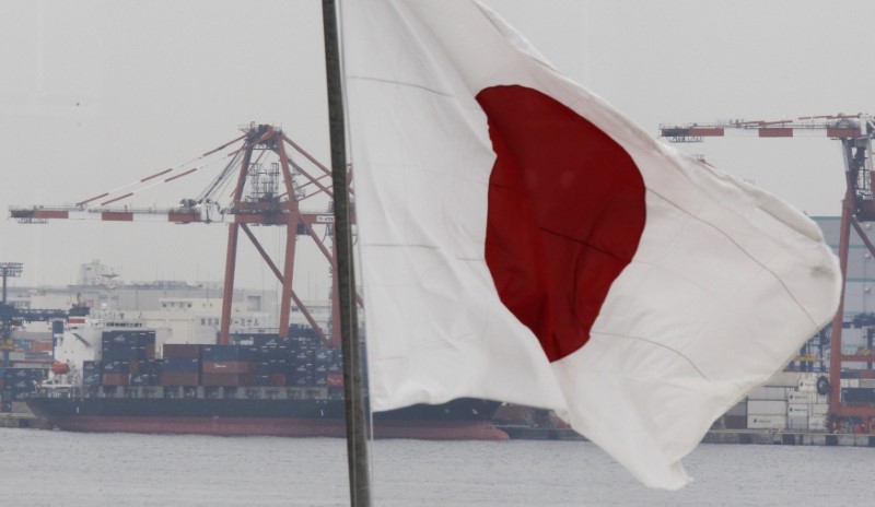 © Reuters. A cargo ship is seen behind Japan's national flag at an industrial port in Tokyo
