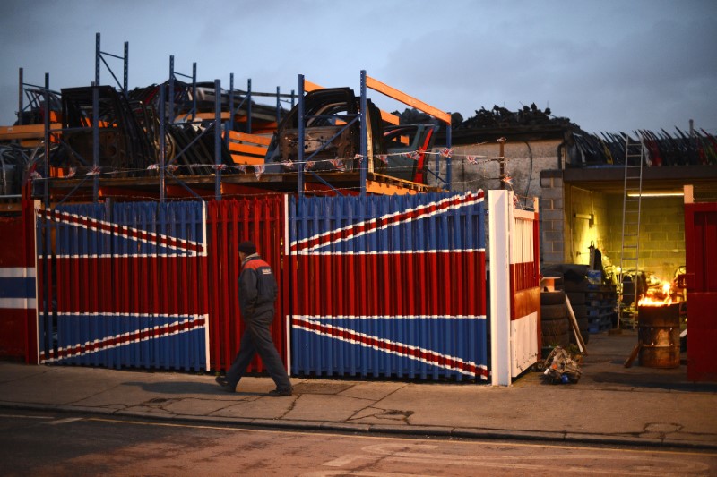 © Reuters. A man walks past a car scrap yard in east London