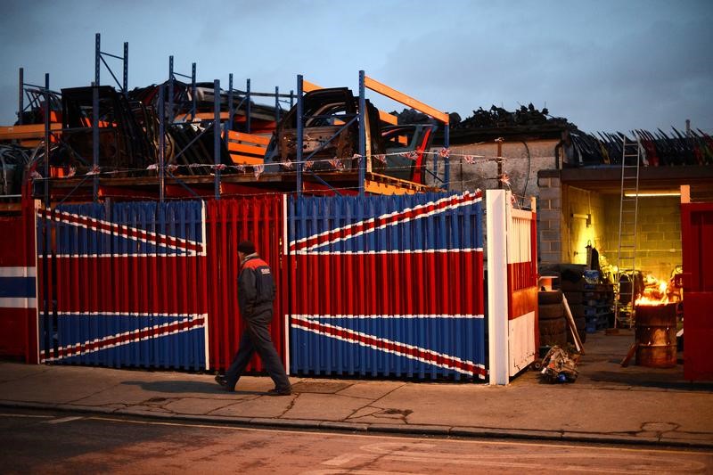 © Reuters. A man walks past a car scrap yard in east London