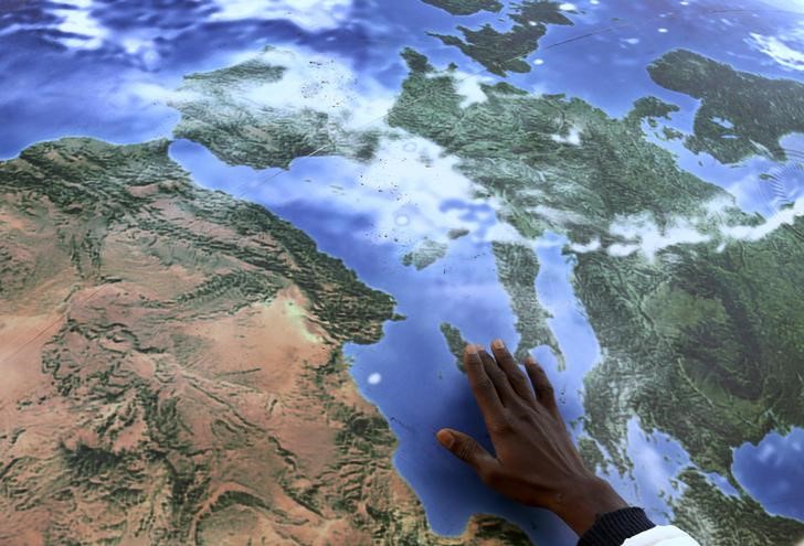 © Reuters. A migrant touches a globe shaped balloon during a rally held ahead of the start of the 2015 Paris World Climate Change Conference, known as the COP21 summit, in Rome