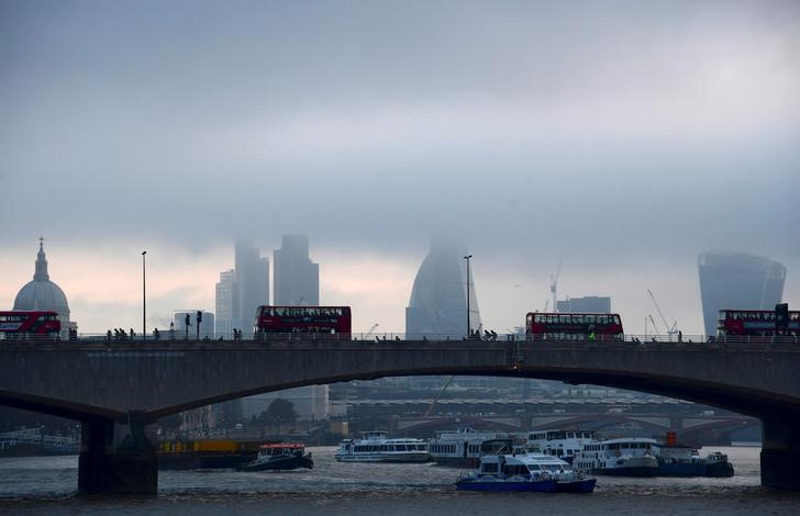 © Reuters. FILE PHOTO: City workers cross the River Thames with the City of London financial district seen behind them