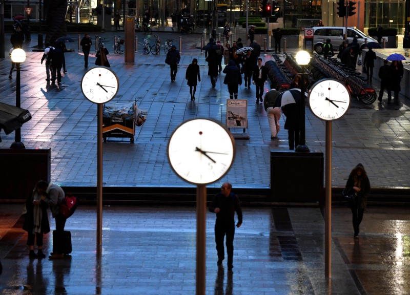 © Reuters. FILE PHOTO: People walk accross a plaza in London's Canary Wharf financial district