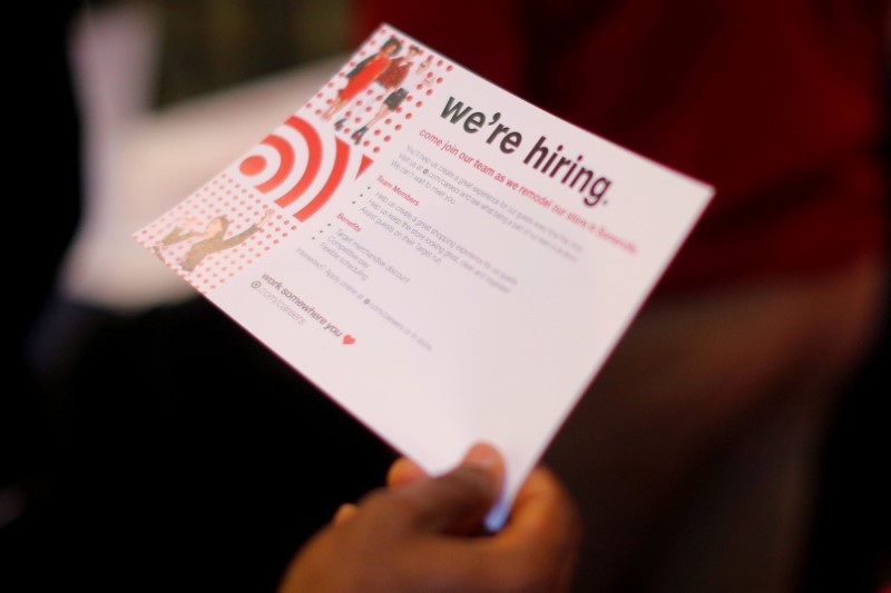 © Reuters. FILE PHOTO: A job seeker holds a "We're Hiring" card while talking to a representative from Target at a City of Boston Neighborhood Career Fair on May Day in Boston