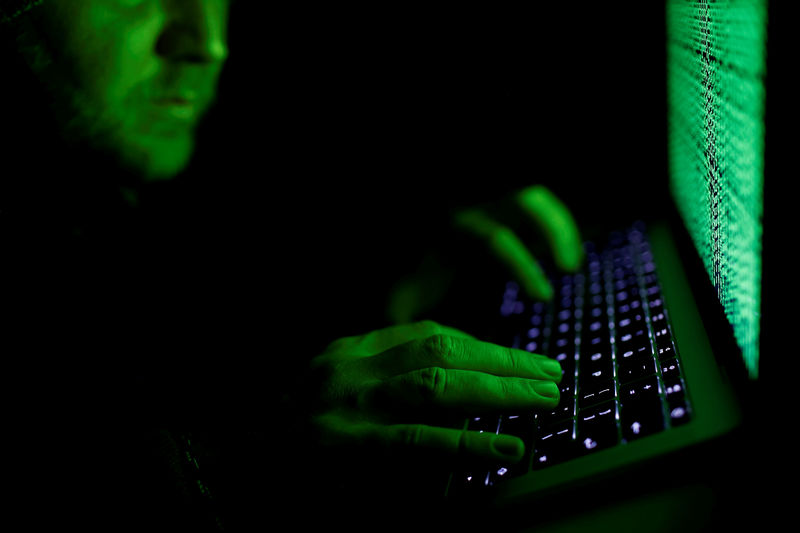 © Reuters. FILE PHOTO: A man types on a computer keyboard in front of the displayed cyber code in this illustration picture