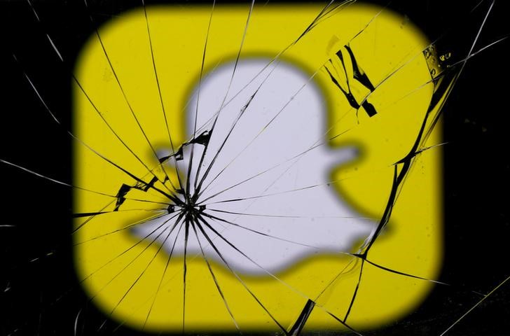 © Reuters. Snapchat logo is seen through broken glass in this illustration