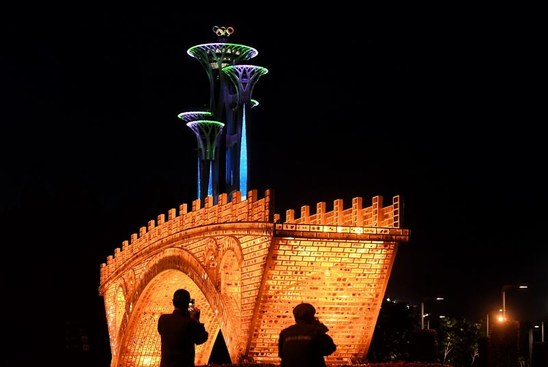 © Reuters. People take pictures in front of a "Golden Bridge on Silk Road" installation, set up ahead of the Belt and Road Forum, outside the National Convention Centre in Beijing