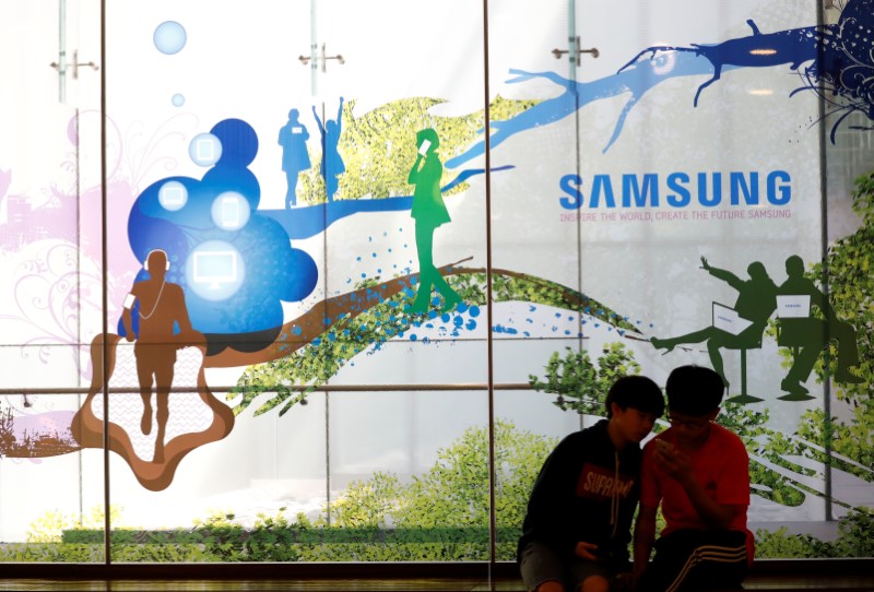 © Reuters. Children look at a mobile phone in front of an advertisement of Samsung Electronic at its store in Seoul