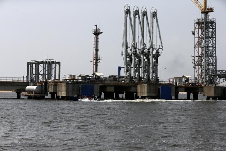 © Reuters. People ride a boat past an oil discharge facility in Lagos