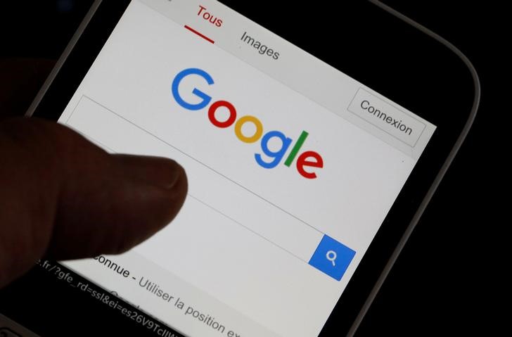 © Reuters. A man holds his smartphone which displays the Google home page, in this picture illustration taken in Bordeaux, Southwestern France