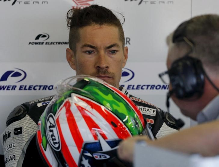 © Reuters. FILE PHOTO: Honda MotoGP rider Hayden of the U.S. talks with a team member in his garage during a free practice session at the Twin Ring Motegi circuit ahead of Sunday's Japanese Grand Prix in Motegi