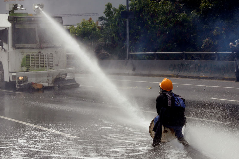 © Reuters. A demonstrator confronts a police water cannon vehicle during a rally called by health care workers and opposition activists against Venezuela's President Nicolas Maduro in Caracas
