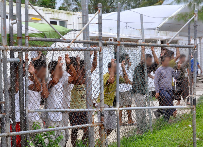 © Reuters. Asylum-seekers look through a fence at the Manus Island detention centre in Papua New Guinea