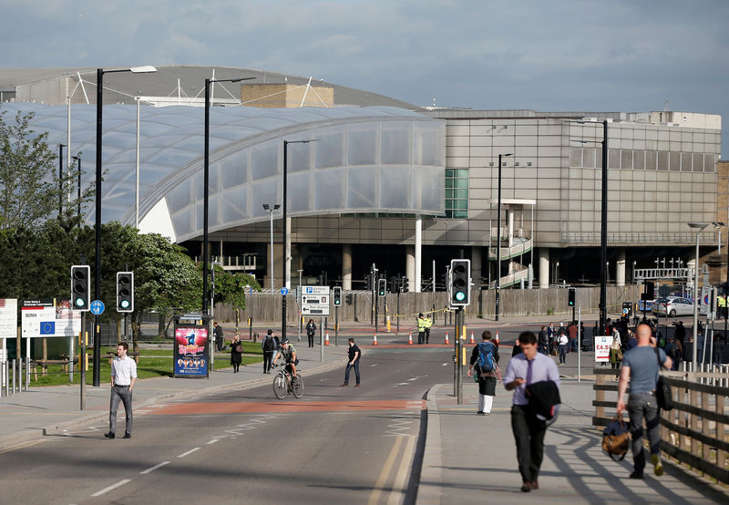 © Reuters. Commuters walk to work as a police cordon surrounds the Manchester Arena