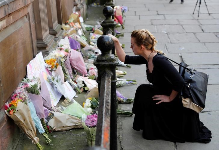 © Reuters. Mulher coloca flores para vítimas de ataque na Arena de Manchester, na Inglaterra