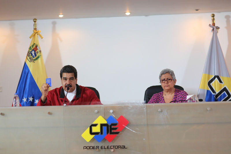 © Reuters. Venezuela's President Nicolas Maduro holds a copy of the Venezuelan constitution as he speaks next to CNE President Tibisay Lucena during their meeting in Caracas