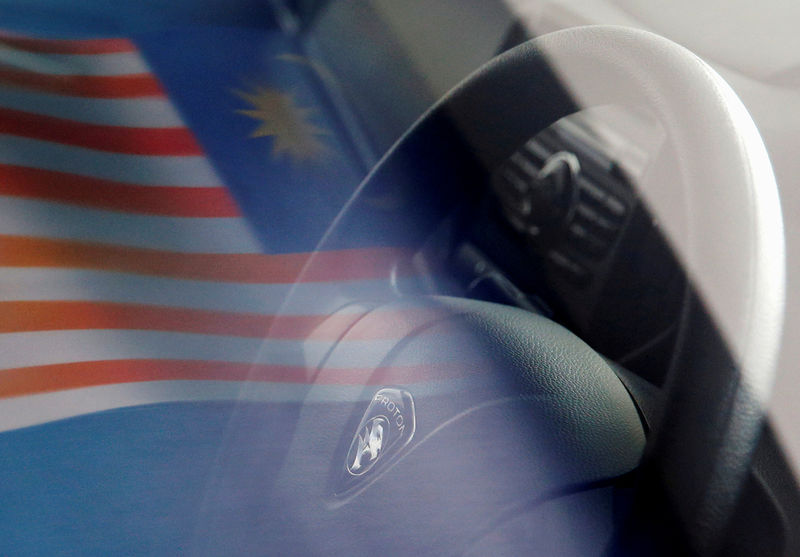 © Reuters. FILE PHOTO: A Malaysian flag is reflected on a car window at a Proton showroom in Puchong