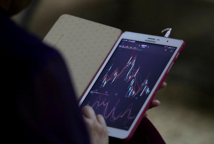 © Reuters. Инвестор в Пекине проверяет данные о торгах на смартфоне