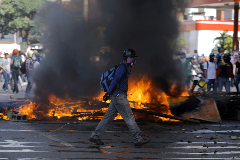 © Reuters. Demonstrators build a fire barricade while clashing with riot security forces during a rally against President Nicolas Maduro in Caracas