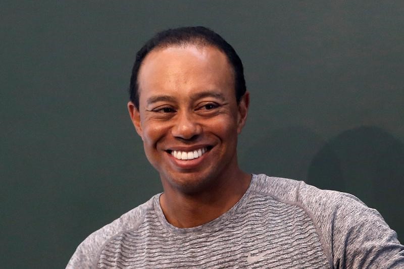 © Reuters. Golfer Tiger Woods smiles as he sits down to sign copies of his new book "The 1997 Masters: My Story" at a book signing event at a Barnes & Noble store in New York