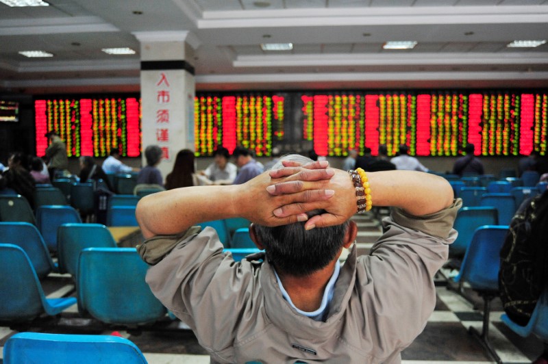 © Reuters. Investor looks at electronic board showing stock information at brokerage house in Nanjing