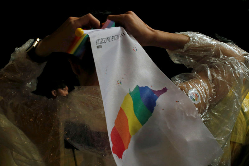 © Reuters. A supporter ties a rainbow headband during a rally after Taiwan's constitutional court ruled that same-sex couples have the right to legally marry, the first such ruling in Asia, in Taipei