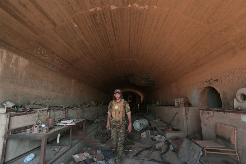 © Reuters. FILE PHOTO: A Syrian Democratic Forces (SDF) fighter inspects a damaged building inside Tabqa military airport after taking control of it from Islamic State fighters, west of Raqqa city