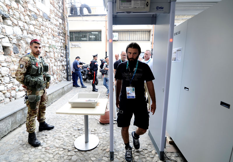 © Reuters. Italian Army soldier patrols as a man walks through a metal detector in Taormina where leaders from the world's major Western powers will hold their annual summit