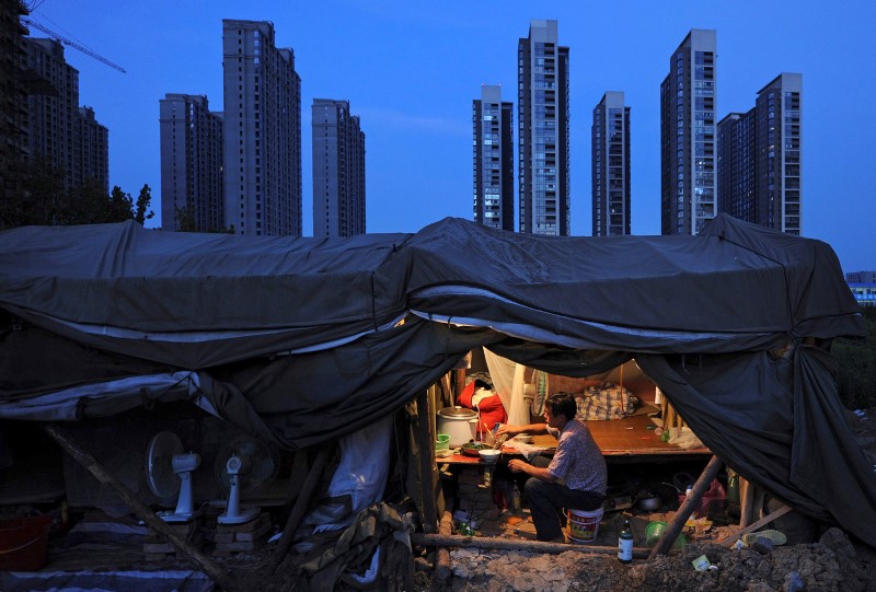 © Reuters. FILE PHOTO: A labourer has his dinner under his shed at a construction site of a residential complex in Hefei