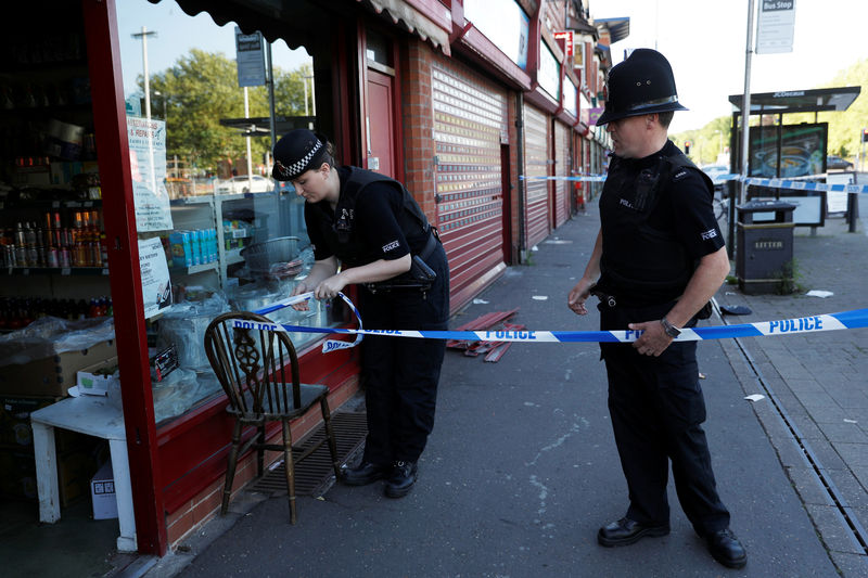 © Reuters. Police officers tie up cordon tape outside a barber's shop in Moss Side which was raided by officers in Manchester