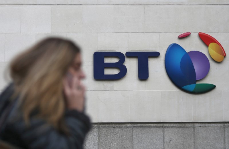 © Reuters. A woman talks on her phone as she passes a branded sign displayed outside of a BT building in London