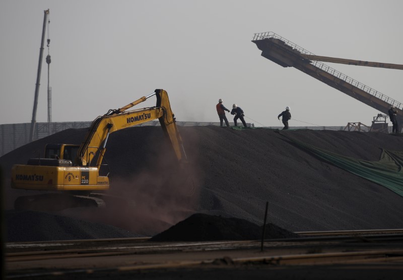 © Reuters. FILE PHOTO: Labors work on a pile of iron ore at a steel factory in Tangshan in China's Hebei Province