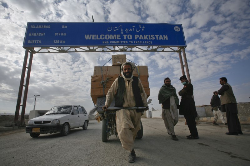 © Reuters. A Pashtun man passes a road sign while pulling supplies towards the Pakistan-Afghanistan border crossing in Chaman
